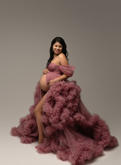 Dramatic pink tulle maternity gown with ruffled texture and off-shoulder design
Description: