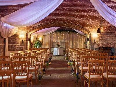 The Fort halls set up for a wedding. The room as chairs on each side with a round table at the end of the aisle and draping fro the ceiling