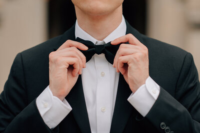 Groom straightens bowtie at a Rollins Mansion Wedding. Photo by Anna Brace, a Wedding Photographer in Des Moines.
