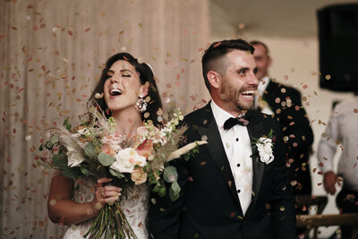 A bride and groom throwing confetti in the air