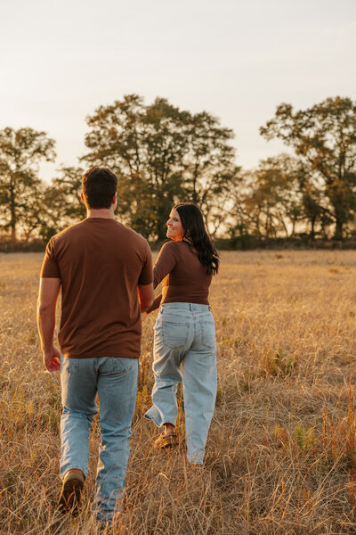 Couple running through a golden farm field during a sunset session in Aiken SC, photography by KateLens Photography.