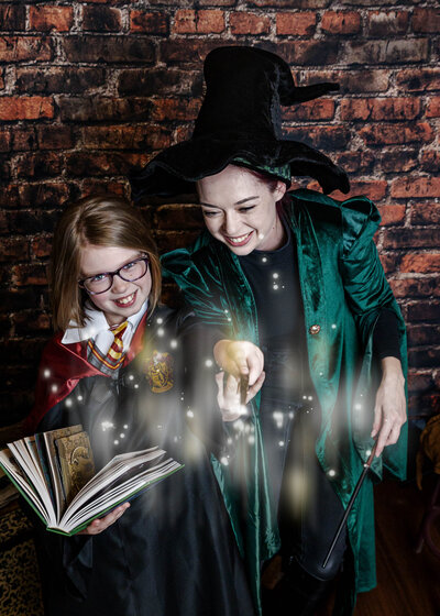 Mom and daughter wearing witch costumes holding wands and pretending to do magic spells