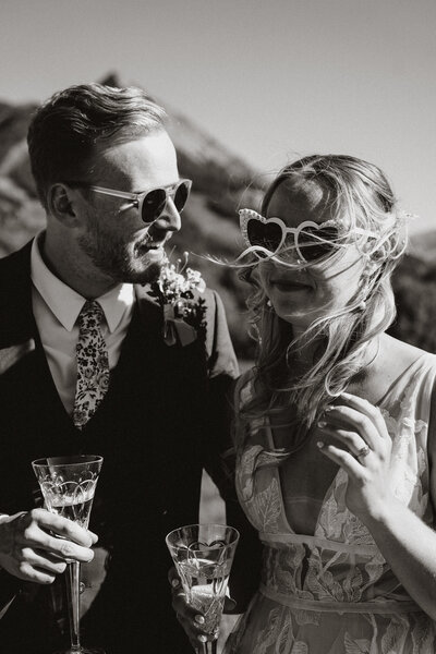 Bride and groom wear fun sunglasses and toast with champagne at their sunny Breckenridge elopement.