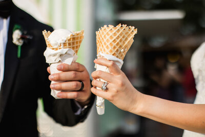 Close up photo of bride and groom hands each holding an ice cream cone