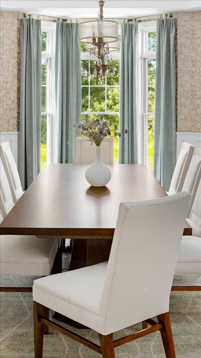 Dark wood dining table with light chairs and flower feature