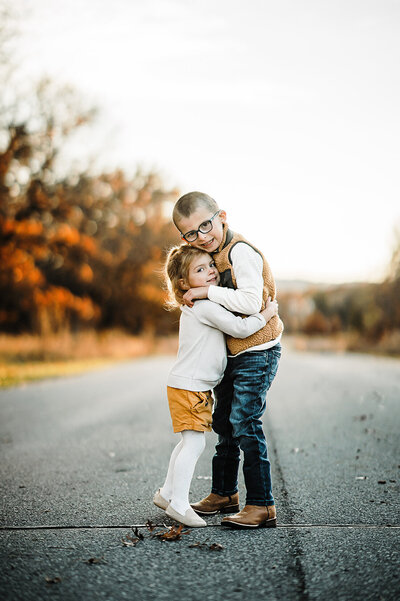 Young family smiling for photo in beautiful Wisconsin woods during fall.