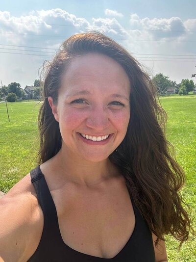 woman with dark hair black tank top outside smiling