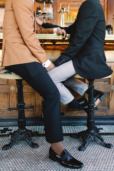 Male couple hold hands at a city bar