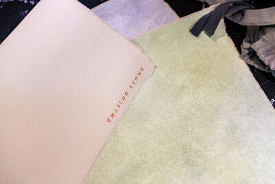 Close-up of Chasing Stone hand-painted flat lay mats in soft pastel tones, used by Joseph Mayden to style wedding details and product photography with elegance.
