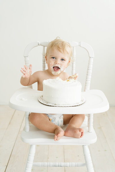 Baby boy plays with birthday cake during cake smash first birthday photos at Julie Brock Photography in Louisville KY