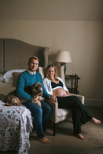 Couple with dog sit for a portrait to celebrate pregnancy at Hotel Endsleigh in Devon