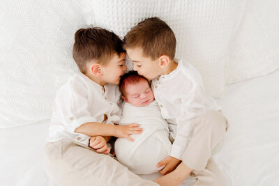 two boys kissing baby taken by newborn photography boston​