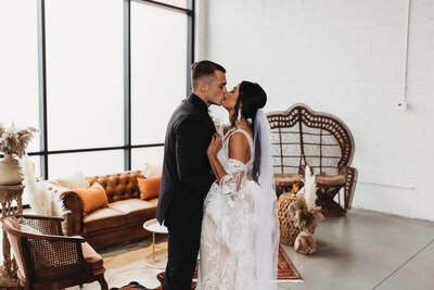 Wedding photo session of couple kissing in front of studio furniture
