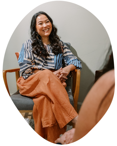 Joanne Lai the somatic therapist sitting with her hand over her heart