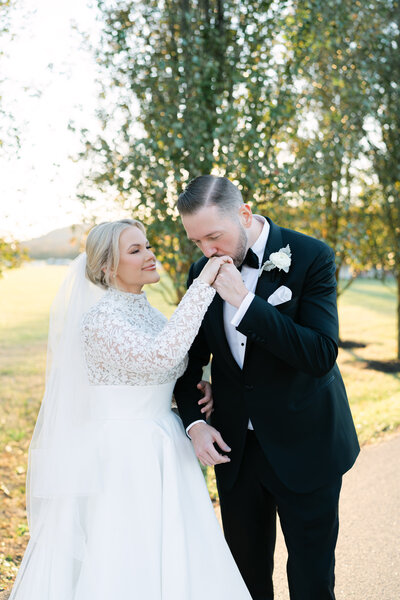 Bride and groom smiling at each other in front of a stone chapel during their outdoor wedding, captured by Nashville wedding photographer Diana Marie