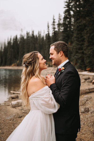 wedding couple holding hands by a mountain lake