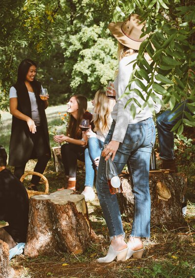 Photo of 3 women in outdoor setting chatting over a picnic and glass of wine