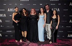 Six Blake & Kwan Team Members dressed elegantly in formal attire at an AHIA salon award event with a branded backdrop.