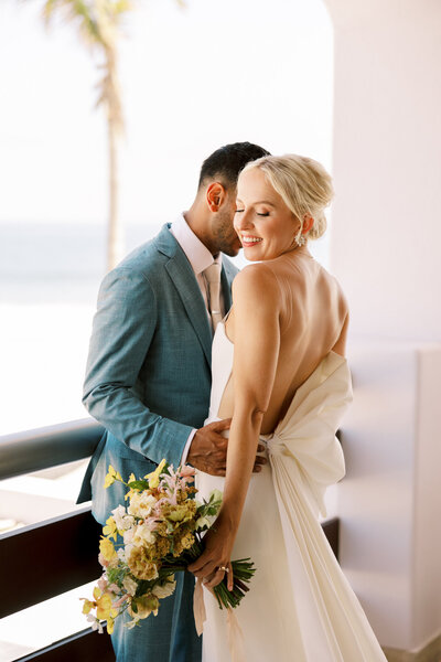 Bride and groom embrace on the balcony of Cabo Azul resort in Los Cabos Mexico