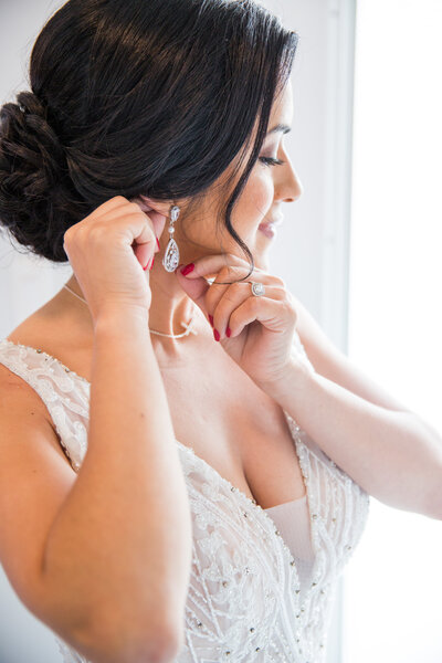 Bride standing in ballroom holding bridal bouquet looking out window