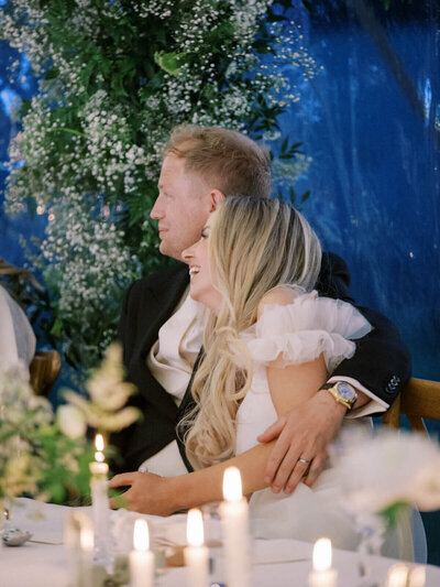 bride and groom smiling and bride holding white minimal flower bouquet both are sitting in the vintage land rover wedding car 