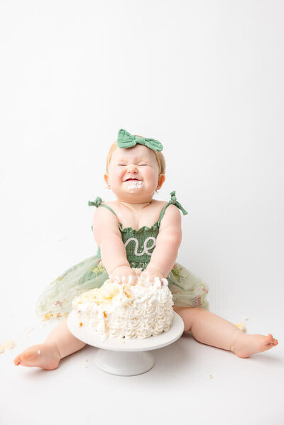 One year old girl smashes her cake in the studio.