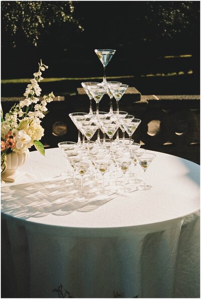 Details of a martini glass tower set up on a white table at a wedding