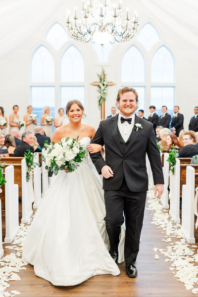 bride and groom walking down the aisle of a chapel