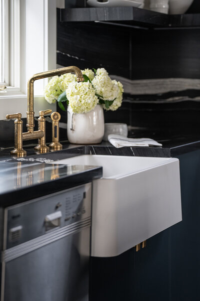 A luxury kitchen sink featuring contrasting black, white, and brass details