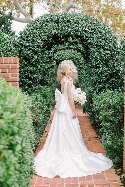 Beautiful bride holds her bouquet and lifts her skirt behind her to blow in the wind