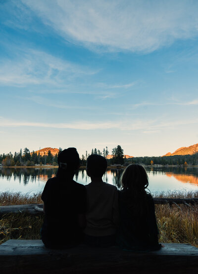 three people outdoors staring at the scenery, including water reflection