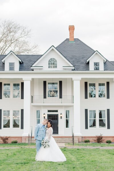 Virginia bride and groom standing in front of their wedding venue, the White Oak Manor on their wedding day
