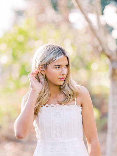 Girl tucks blonde hair behind ear