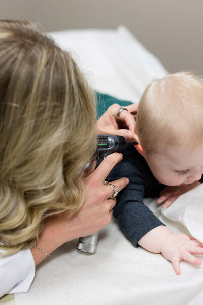 Jamie looking in the ears of a pediatric patient