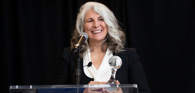 Celeste Mergens with Global Washington Global Hero Trophy smiling with microphone