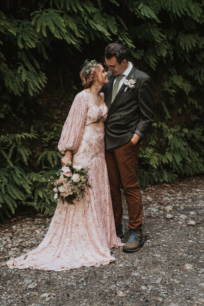 Bride and groom gazing into each other's eyes bride wearing a rose pink lace gown holding boquet taken by California elopement photographer Kasey Mantiply