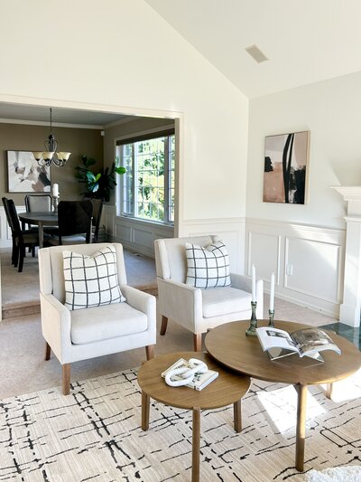 Light-filled living and dining area staged by Modern Mollusk in Snohomish County featuring neutral seating, wood tables, and modern artwork.