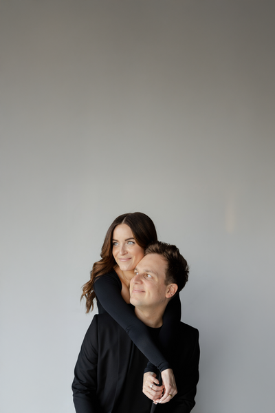 Todd and Madi, wedding and lifestyle photographers at TM Photo Co, sharing a warm embrace in a modern studio portrait.