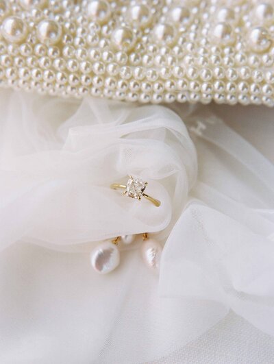 diamond wedding ring and pearl earrings on white veil macro photo