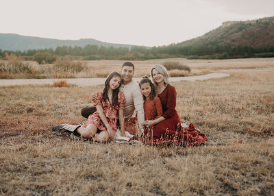 A family of four poses while strategically wearing fall colored clothing at Dawsons Butte in Castle Rock Colorado during a sunset session.
