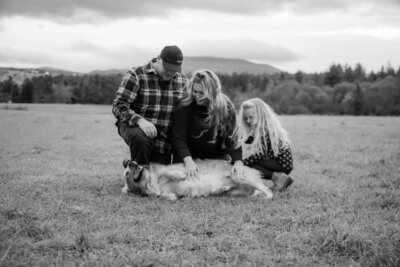 Family petting their dog in field | Family Photos