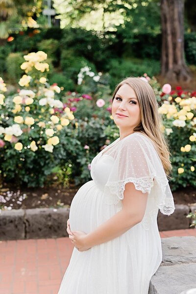 Mom in white dress in portland rose garden park for maternity photography captured by Ann Marshall Photography