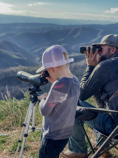 Little-boy-and-dad-looking-through-spotting-scope-at-mountains
