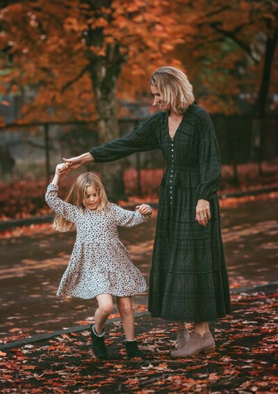 Joyful moment of a mother twirling her daughter in a Renton park during a playful family photo session.