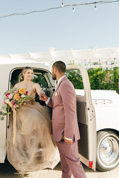 groom helping bride out of antique car