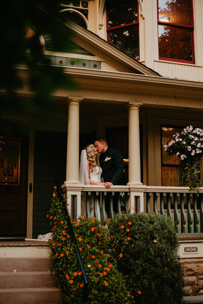 A couple kisses on the porch of The Tapestry House in Laporte, Colorado