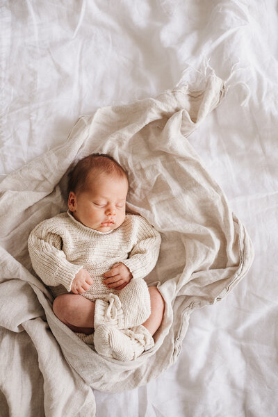 newborn baby sleeping on bed