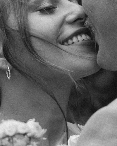 Bride and groom laugh together in front of their wedding venue