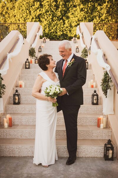 Bride and groom look into each others' eyes while holding a wedding bouquet