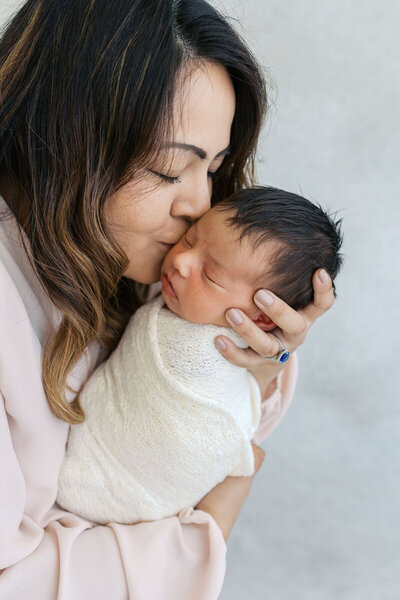 Newborn photography bay area of mom kissing baby's head.